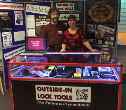Simon and Wendy stand behind the counter at a Locksmiths Trade Show for Outside-In Lock Tools