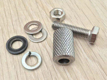 Various washers a nut and bolt and a gripnut laid out on to a light wooden background