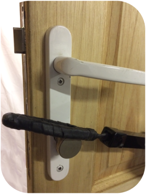 Black rubber Locksmiths tool being used on a lock fitted to the inside of a wooden door
