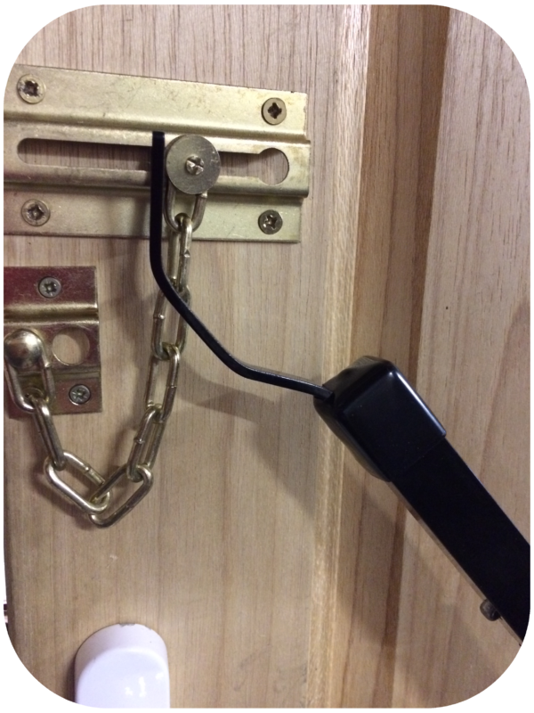 Black Locksmiths tool being used on a door chain fitted to the inside of the door